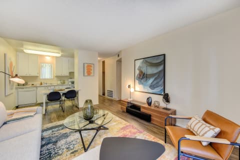 Living Room with View of Dining Area, Hardwood Inspired Floor, Colorful Rug, Brown Chair and White Sofa